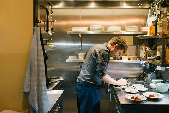 Man carefully plating food in a professional kitchen, illustrating the impact of lies that affected people’s lives unexpectedly