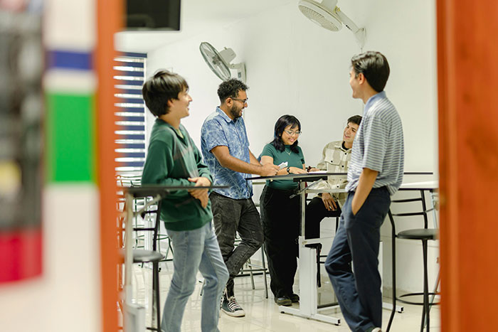 Group of young people casually discussing in an office, illustrating impact of lies on people's lives and relationships.