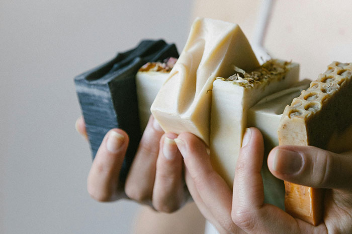 Hands holding various bars of natural soap, illustrating common misconceptions and lies that affect personal care choices.