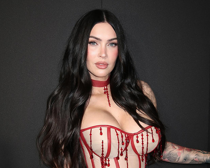 Celebrity with long dark hair wearing a red beaded corset sharing stunning confessions about their movies years after filming