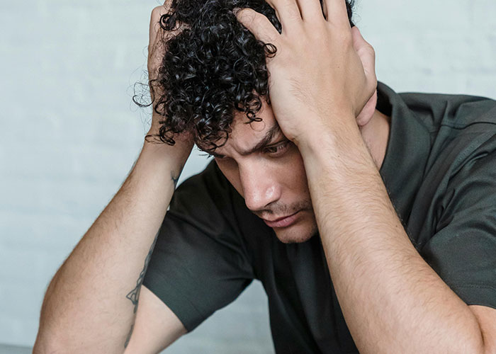 Frustrated man holding head, upset with stalkerish HOA president and facing consequences in court after revealing secrets.