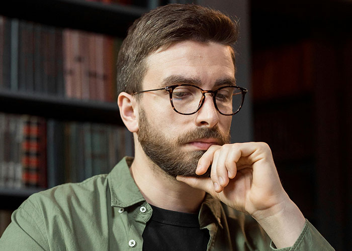 Man with glasses and beard, deep in thought while uncovering HOA president secrets for court resolution.