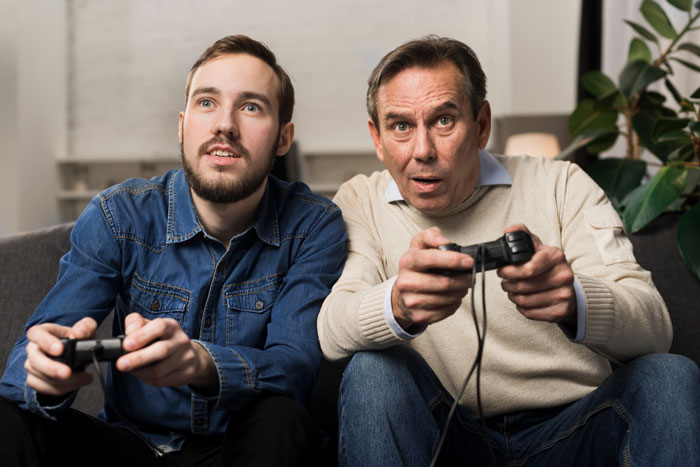 Stepdad and son playing video games together, stepdad trying to connect while kids stay loyal to bio dad&rsquo;s influence.