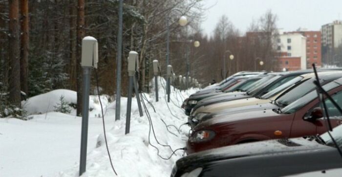 Cars plugged into outdoor electric heaters in a snowy parking lot, illustrating strange facts about our world.