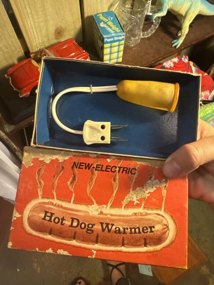 Vintage electric hot dog warmer in a worn box, showing an unusual food heating device in a cluttered setting.