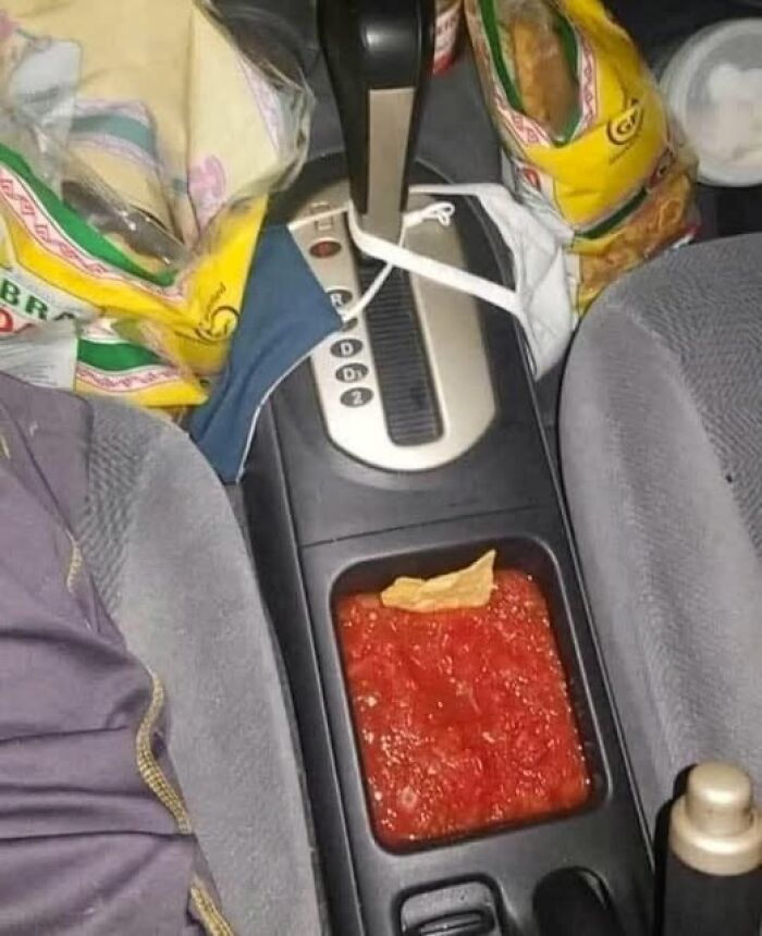 Car console filled with salsa and a tortilla chip placed inside, illustrating a stupid food meme for stupid people.