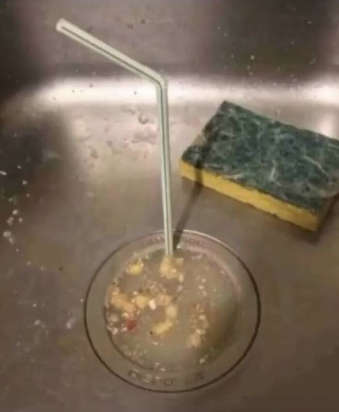 Dirty kitchen sink drain with food particles and a straw inserted, illustrating stupid food memes for stupid people humor.