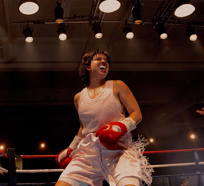 Plus-size model in boxing ring wearing red gloves and white outfit preparing to fight under bright arena lights Plus-size model in boxing ring wearing red gloves and white outfit preparing to fight under bright arena lights