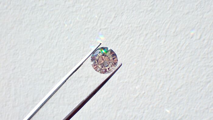 Close-up of a sparkling diamond held by tweezers symbolizing absurd but true stories that are hard to believe.