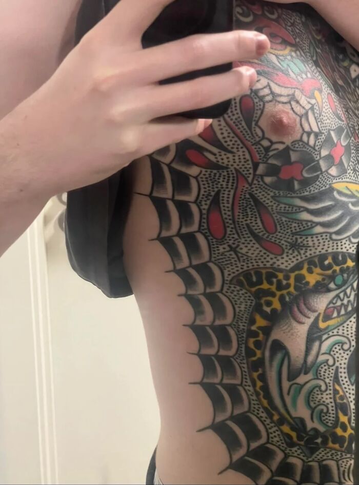 Man showing large colorful tattoo on chest and side, highlighting tattoo regret and emotional struggle with depression.