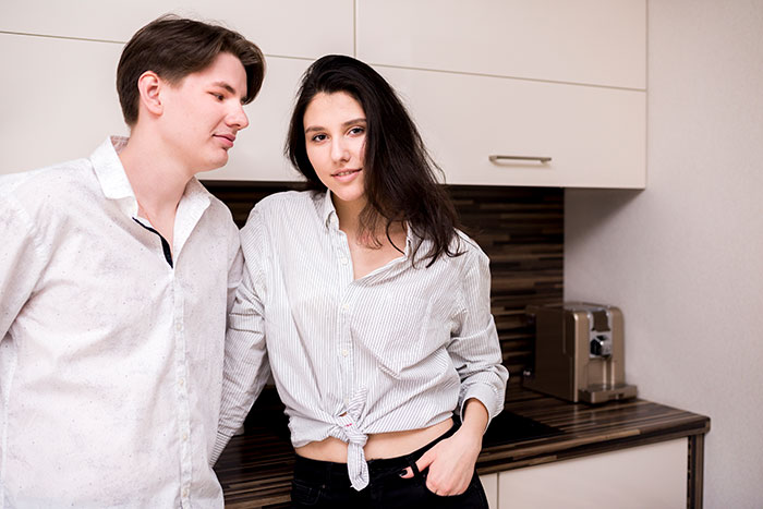 Young siblings in a kitchen with the golden child brother looking entitled while the scapegoat sister stays firm and calm.