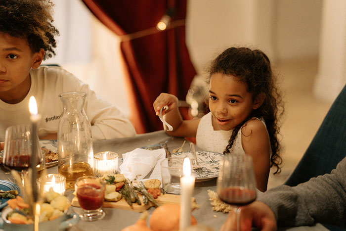 Children sitting at a Thanksgiving table surrounded by food and candles, illustrating common Thanksgiving hosting pet peeves.
