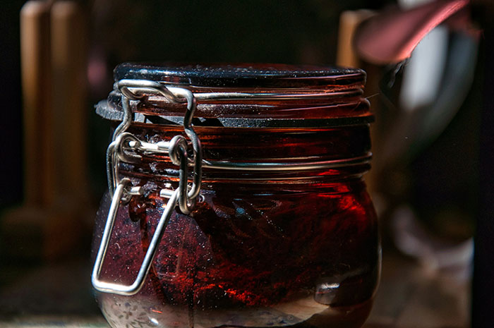 Close-up of a glass jar with a metal clasp containing dark homemade preserves, related to Thanksgiving hosting pet peeves.
