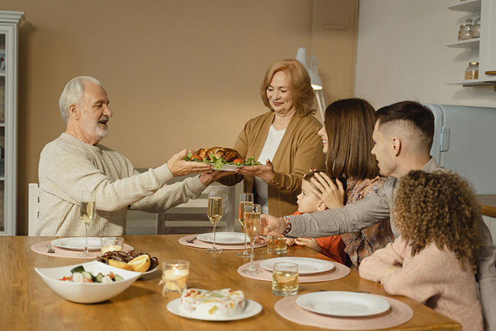 Family sharing a Thanksgiving meal around the table, illustrating common Thanksgiving hosting pet peeves during holiday gatherings.