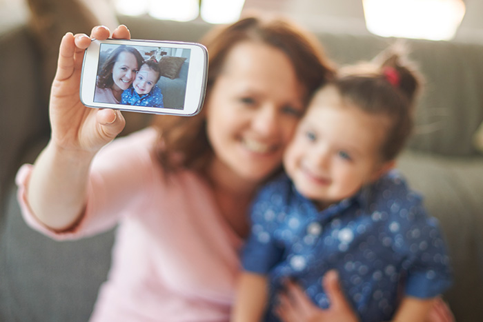 Mother and child taking a selfie, highlighting concerns about parents posting images of their children online. Mother and child taking a selfie, highlighting concerns about parents posting images of their children online.