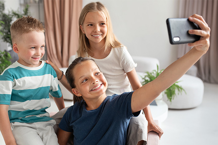 Three children smiling and taking a selfie, illustrating why parents shouldn't post about their children online. Three children smiling and taking a selfie, illustrating why parents shouldn't post about their children online.
