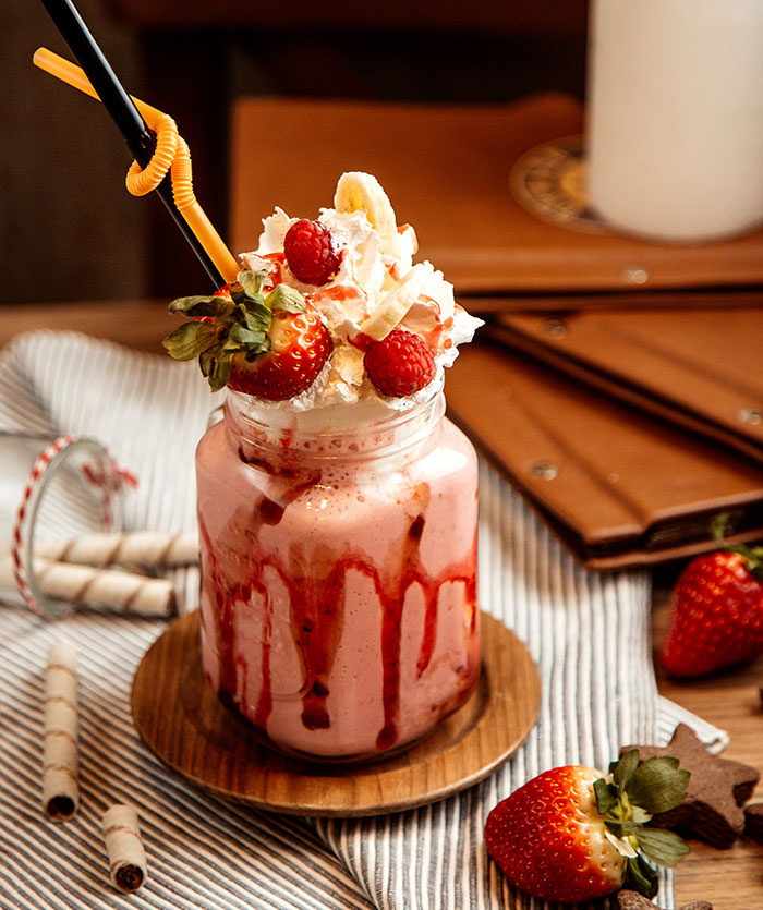 Strawberry milkshake topped with whipped cream and berries with a focus on men anonymously reveal secrets concept.