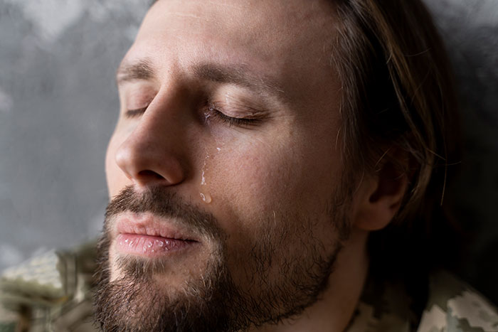 Close-up of a man with a beard shedding a tear, expressing deep emotion and vulnerability without being judged.