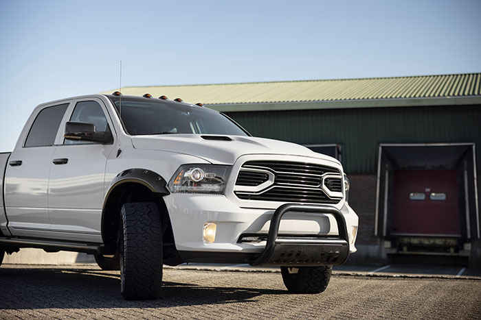White pickup truck parked outside near an industrial building under clear sky with no visible metal detectors at school.