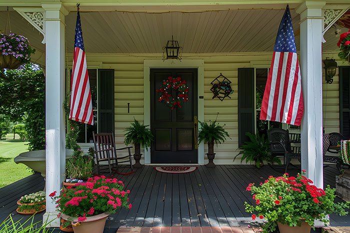 Front porch decorated with American flags and flowers, illustrating quintessentially American home style and culture.