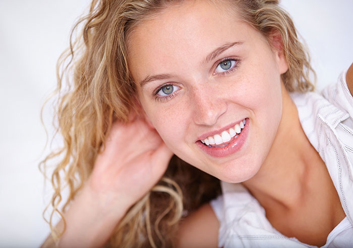 Smiling young woman with curly blonde hair lying down, representing metal detectors at school security concept.