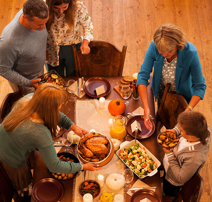 Family gathering around the table with Thanksgiving-style food, illustrating American traditions and metal detectors at school.