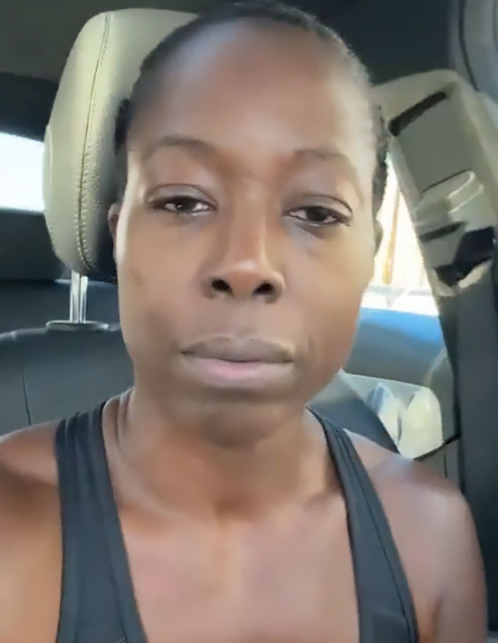 Woman in a car with a serious expression, relating to uproar over lesbian removed from gym confrontation in ladies&rsquo; room.
