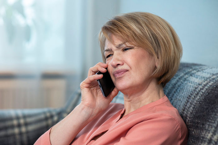 Middle-aged woman looking frustrated while talking on phone, depicting tension in toxic MIL and inherited tractor dispute.