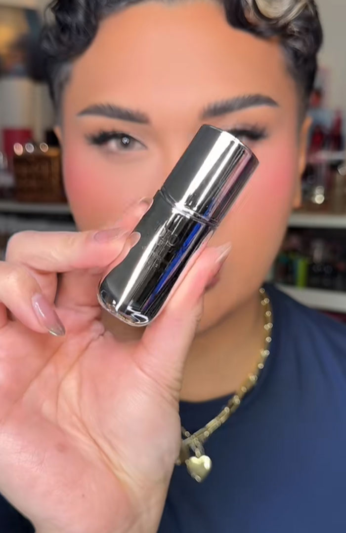 Person holding a shiny silver Dior product, highlighting luxury beauty item linked to Dior advent calendar controversy.