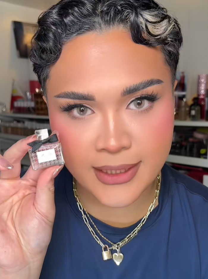 A person holding a small Dior perfume bottle, showcasing a luxury item related to the Dior advent calendar.