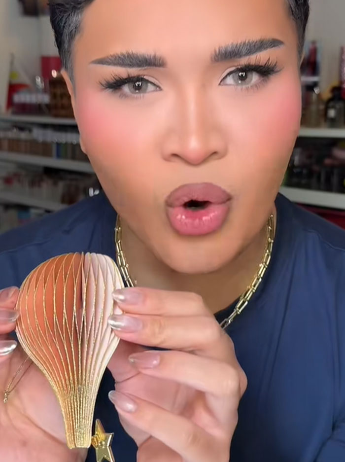 Person with manicured nails holding a decorative item while discussing Dior advent calendar and its $1,000 price.