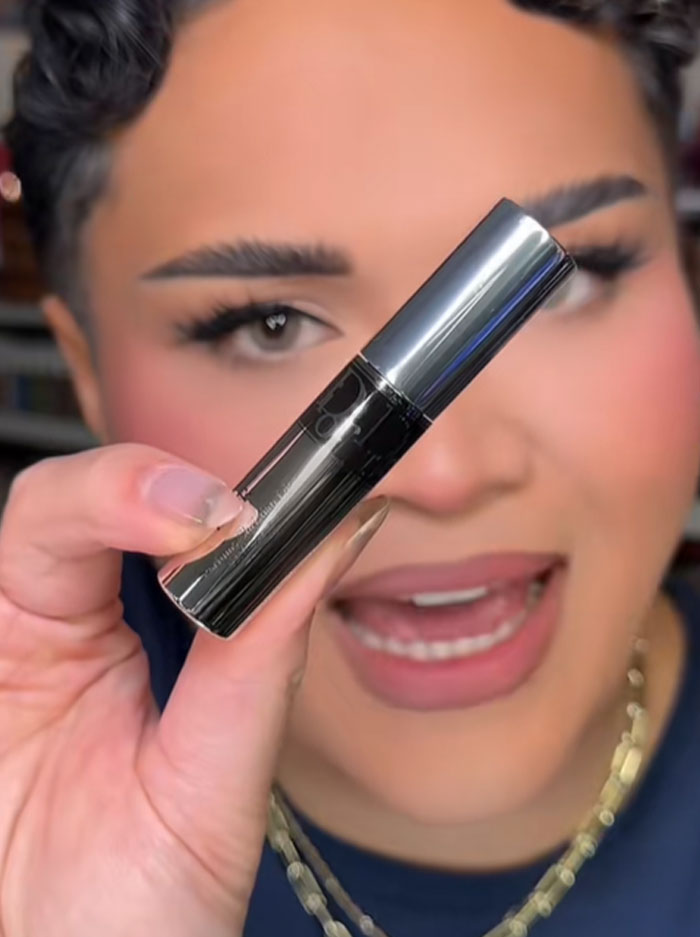 Person holding a Dior product close to the camera, highlighting the luxury advent calendar item in focus.