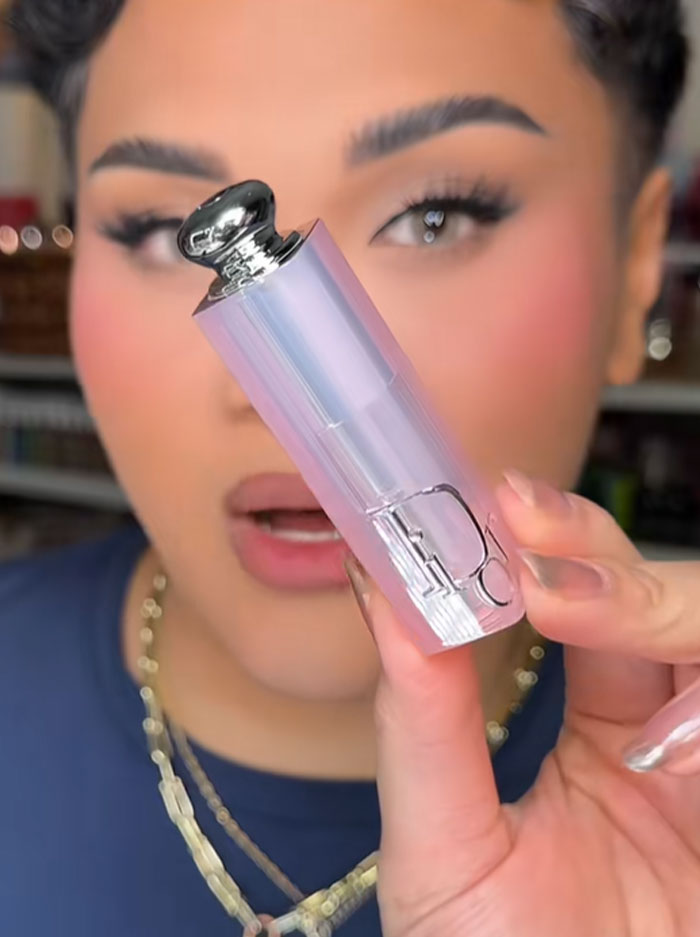 Person holding a Dior lipstick from the $1,000 advent calendar with a blurred background and focused facial makeup.