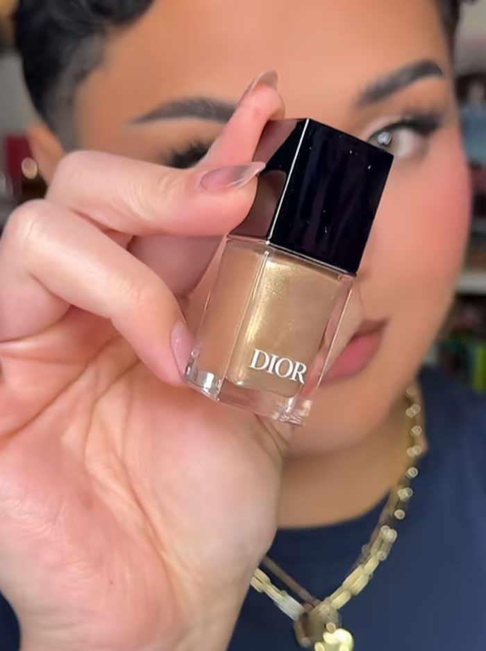 Person holding a Dior nail polish bottle, highlighting luxury beauty product from Dior advent calendar collection.