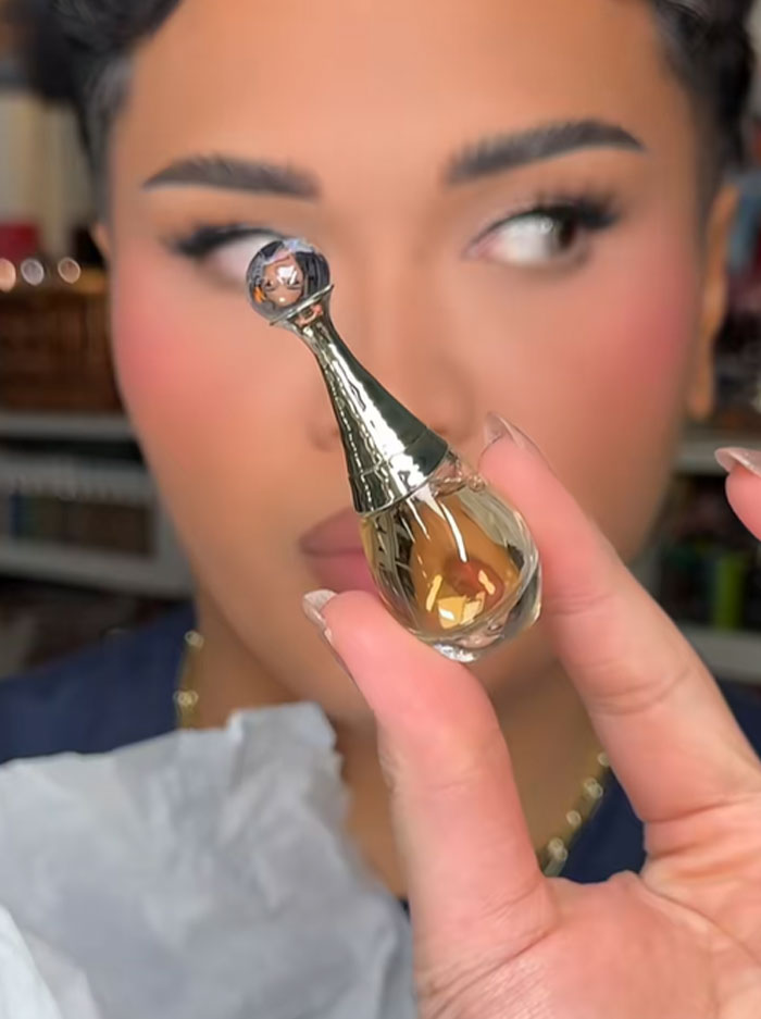 Person holding a small Dior perfume bottle, highlighting luxury beauty item from Dior advent calendar.