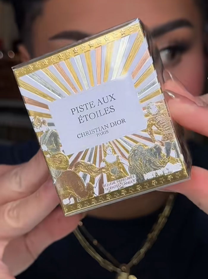 Person holding a Christian Dior product from the advent calendar collection with gold and white decorative packaging.