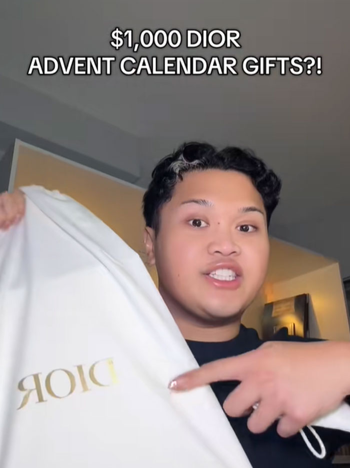 Person holding and pointing at a Dior branded bag showcasing a $1,000 Dior advent calendar gift item.