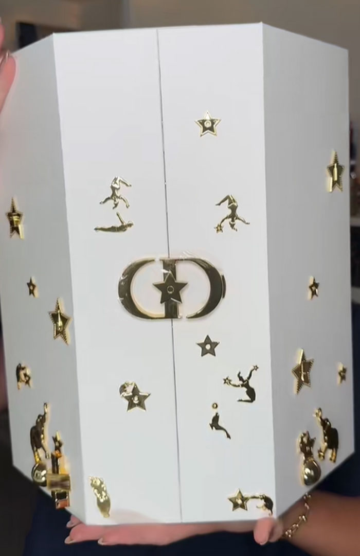 White Dior advent calendar box with gold star and figure decorations held by a person, luxury holiday countdown item.