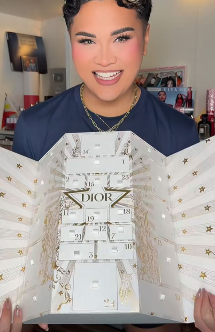 Person holding and displaying a Dior advent calendar with numbered compartments and decorative star patterns.