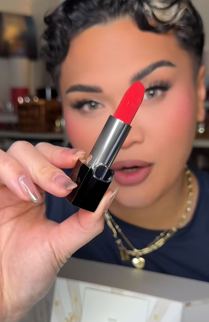 Person holding a red Dior lipstick close to the camera, highlighting luxury beauty in an advent calendar reveal.