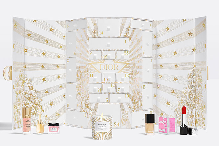 Dior luxury advent calendar with beauty products and candle, featuring gold star design and numbered compartments.