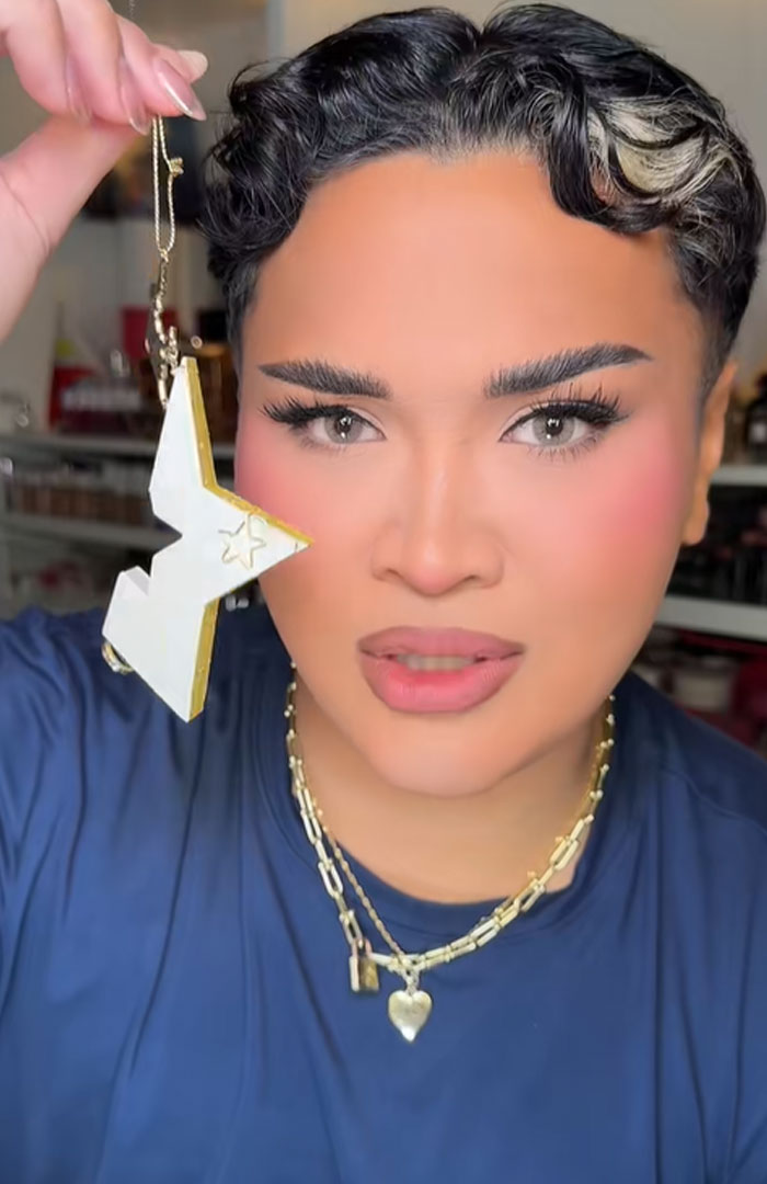 Person holding a star-shaped ornament from Dior advent calendar, showcasing luxury holiday item with neutral makeup and gold necklaces.