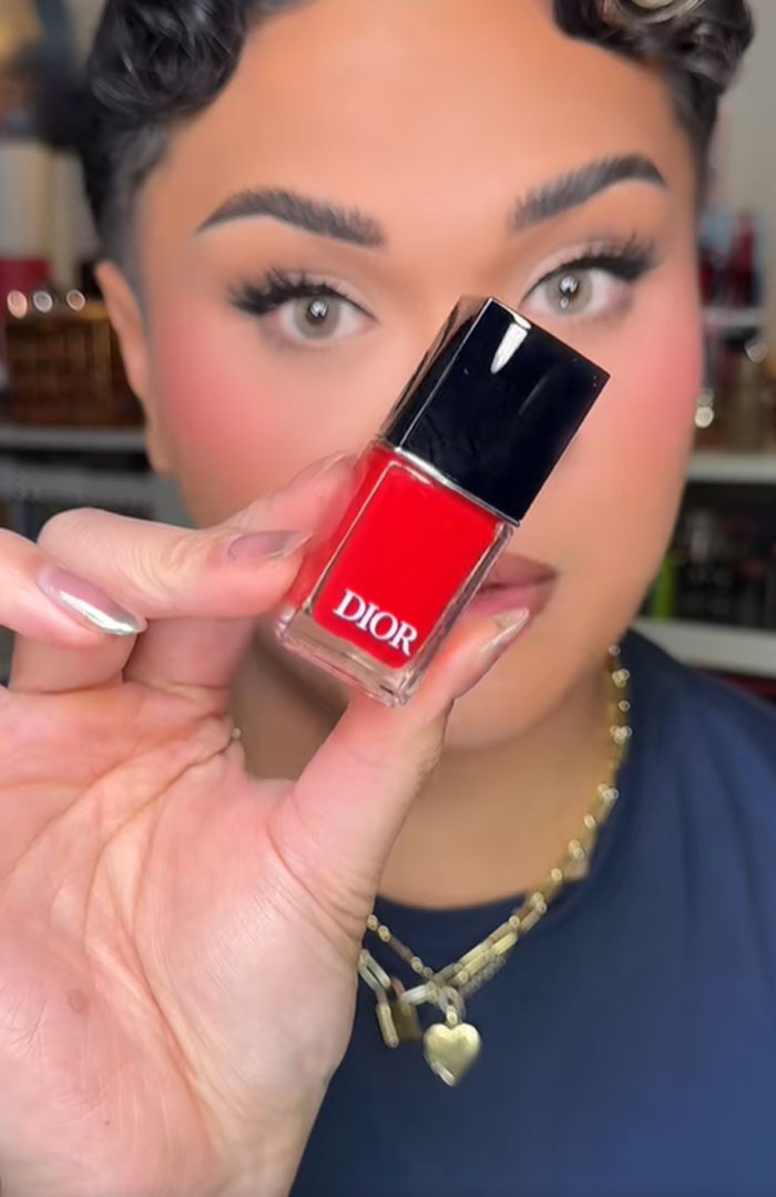 Person holding a red Dior nail polish bottle, highlighting luxury beauty items from a Dior advent calendar.