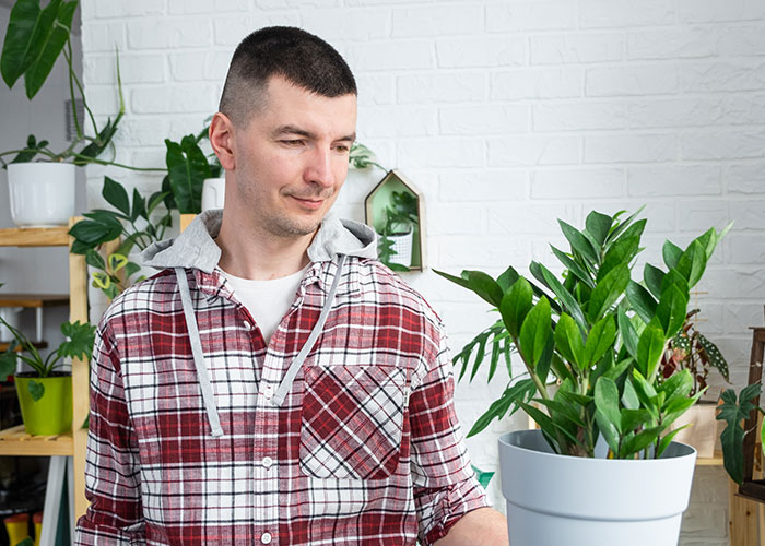 Man in plaid shirt tending to houseplants, capturing the strangest things people accidentally saw neighbors doing.