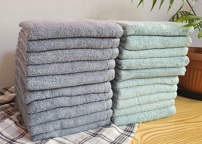 Neatly folded gray and blue towels stacked on a wooden surface, illustrating strange things neighbors doing insights.