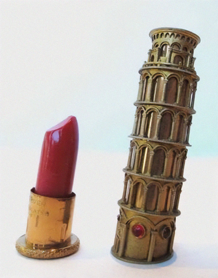 Miniature vintage lipstick beside a detailed old object shaped like the Leaning Tower, showcasing very old objects from ancestors.