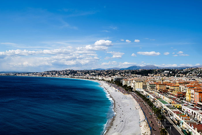 Coastal cityscape with beach and promenade under blue sky, depicting locations solo female travelers do not recommend.