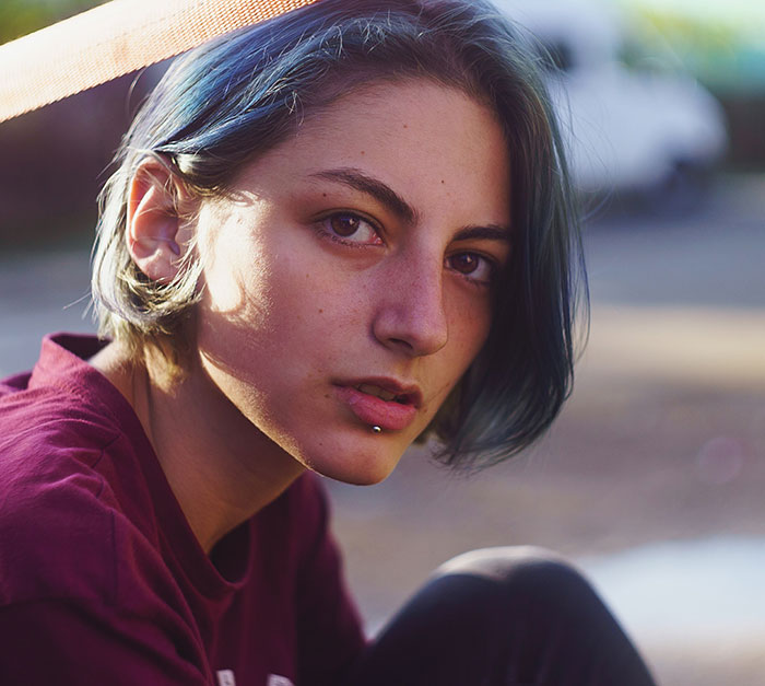 Young woman with blue hair and lip piercing in casual clothes, reflecting the experience of solo female travelers feeling powerless.