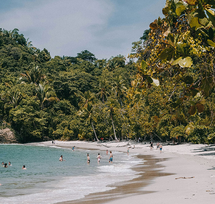 Tropical beach with travelers swimming and walking, highlighting solo female travelers' places not recommended for safety concerns.