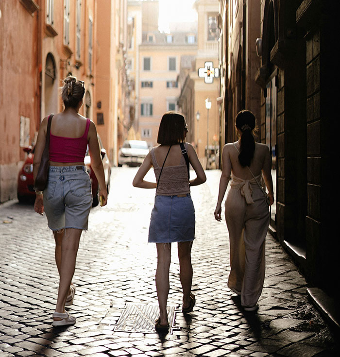 Three young women walking on a cobblestone street, highlighting solo female travelers in urban settings.